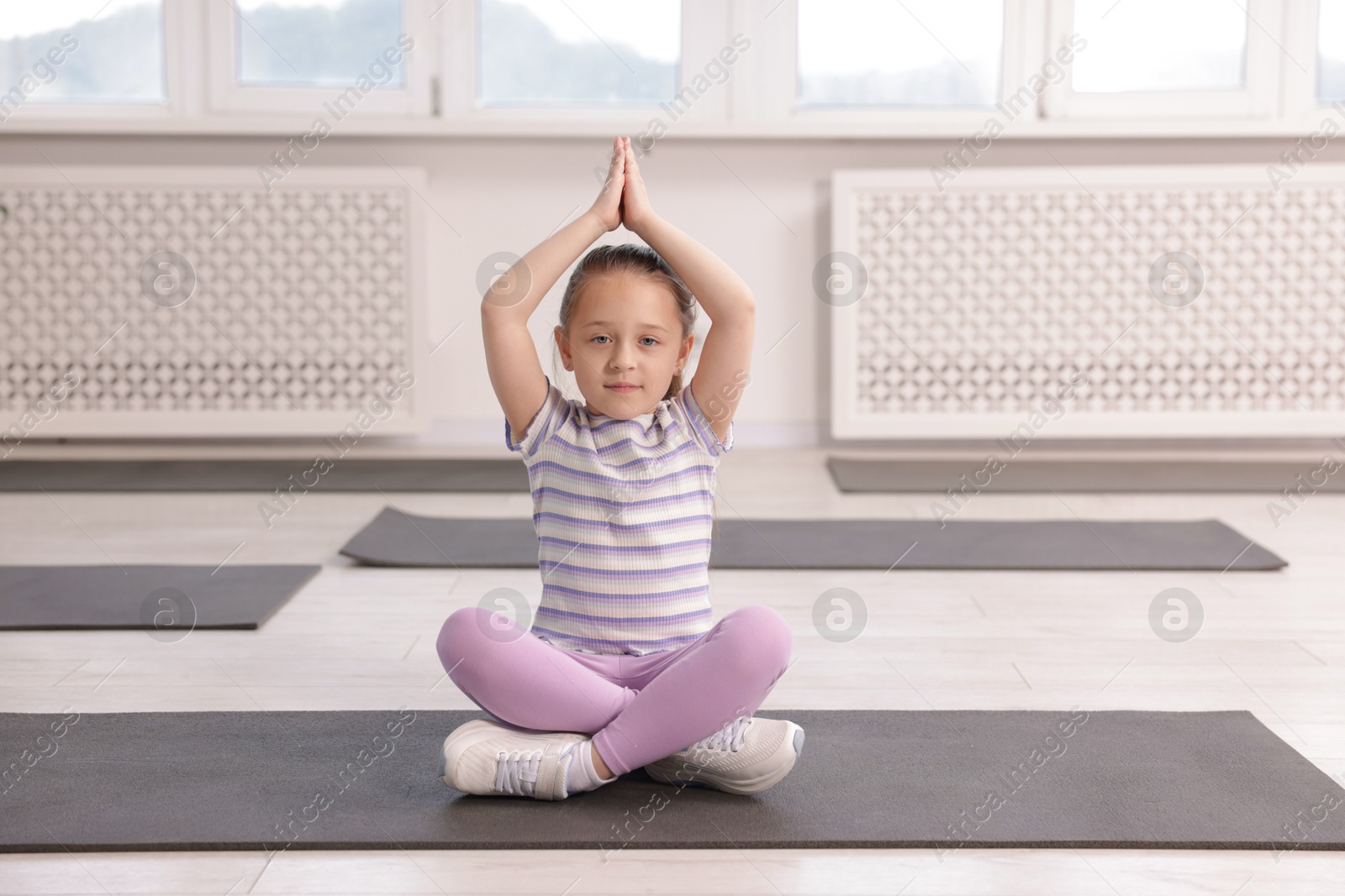 Cute girl practicing yoga on mat indoors Photo of Cute girl practicing yoga on mat indoors