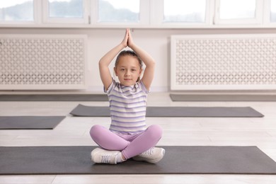 Photo of Cute girl practicing yoga on mat indoors