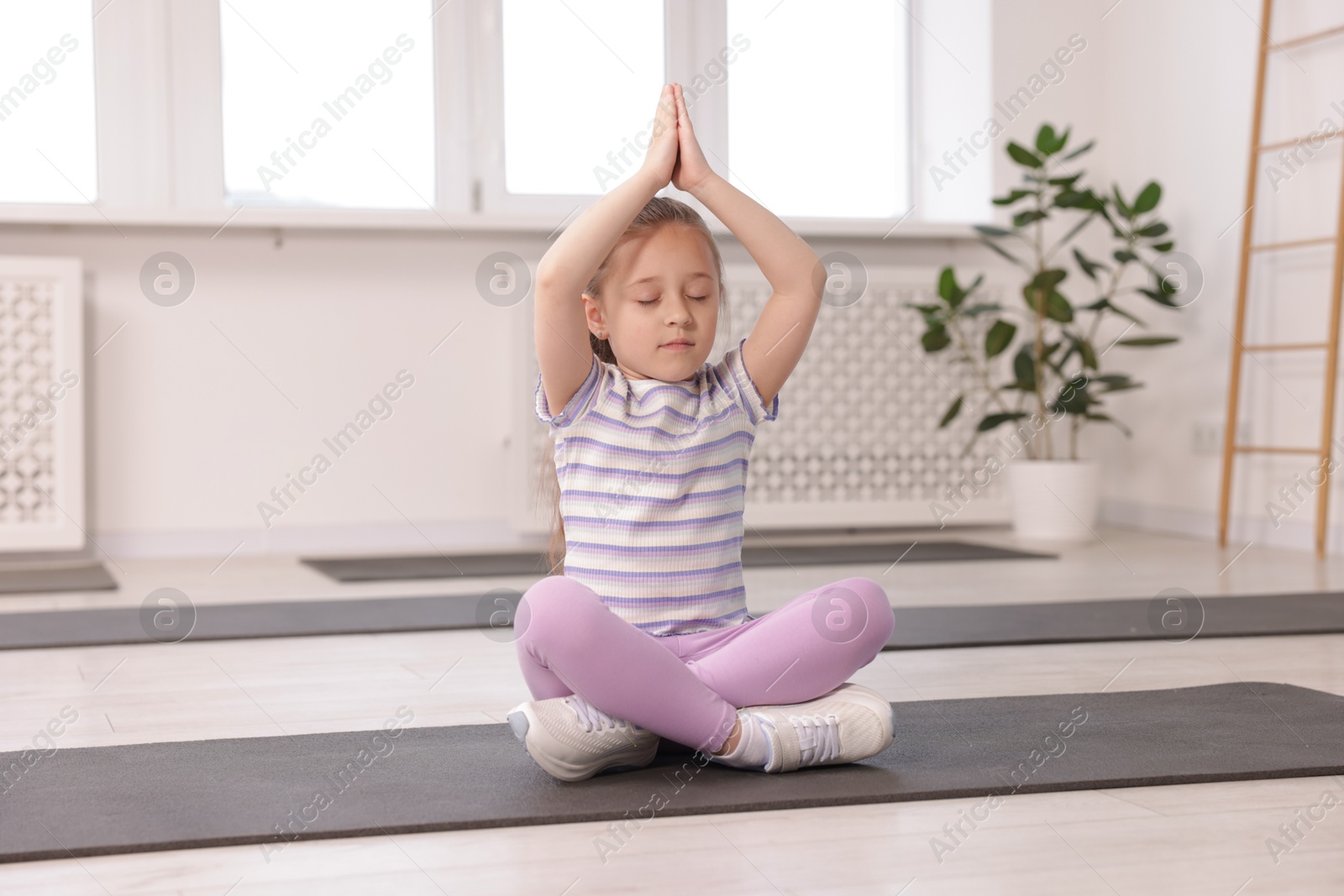 Cute girl meditating on yoga mat indoors Photo of Cute girl meditating on yoga mat indoors