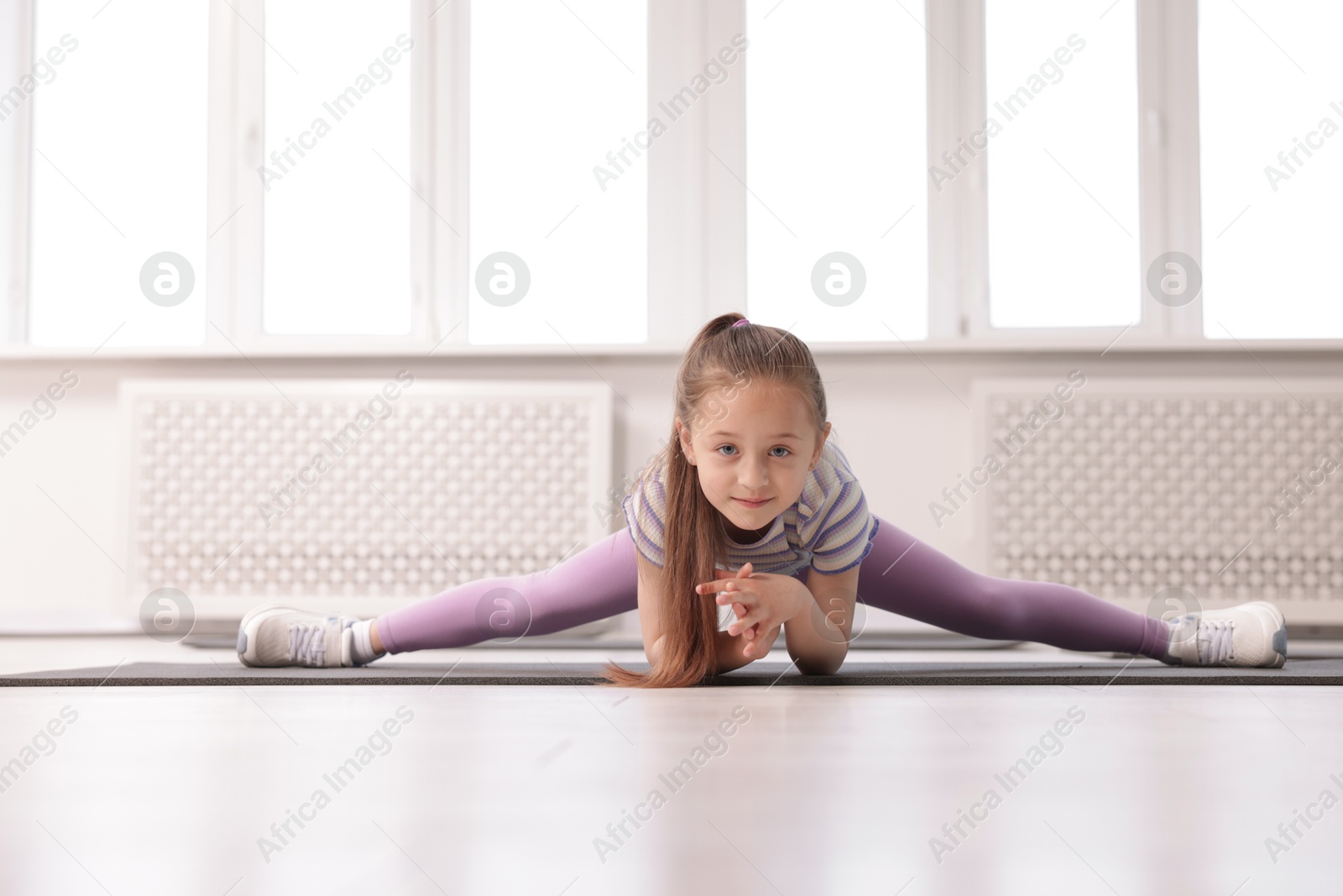 Cute girl practicing yoga on mat indoors Photo of Cute girl practicing yoga on mat indoors
