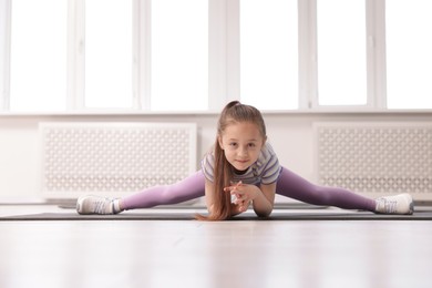 Photo of Cute girl practicing yoga on mat indoors
