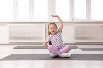 Photo of Cute girl practicing yoga on mat indoors