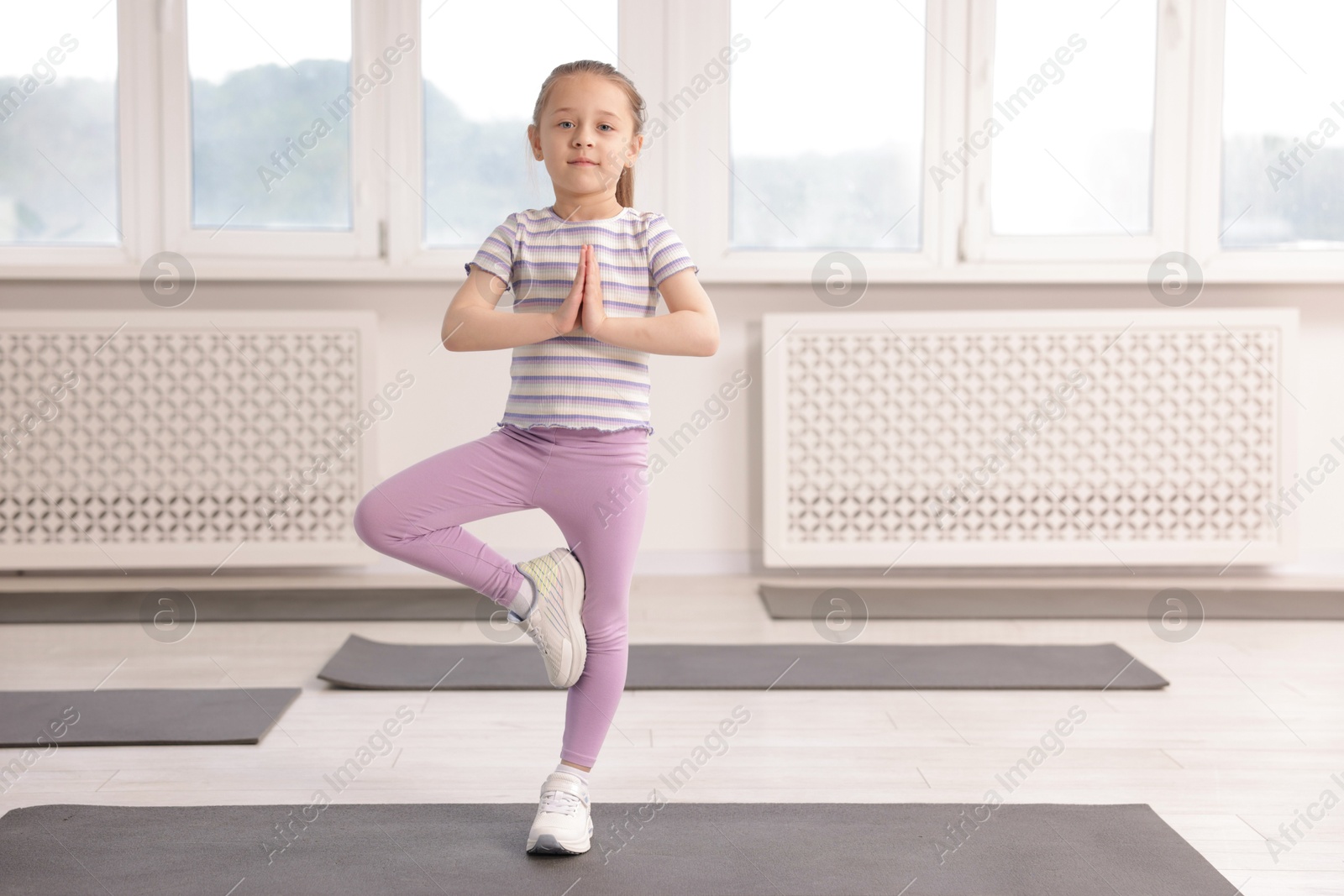 Cute girl practicing yoga on mat indoors Photo of Cute girl practicing yoga on mat indoors