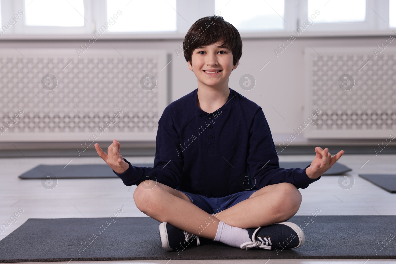 Happy boy practicing yoga on mat indoors Photo of Happy boy practicing yoga on mat indoors