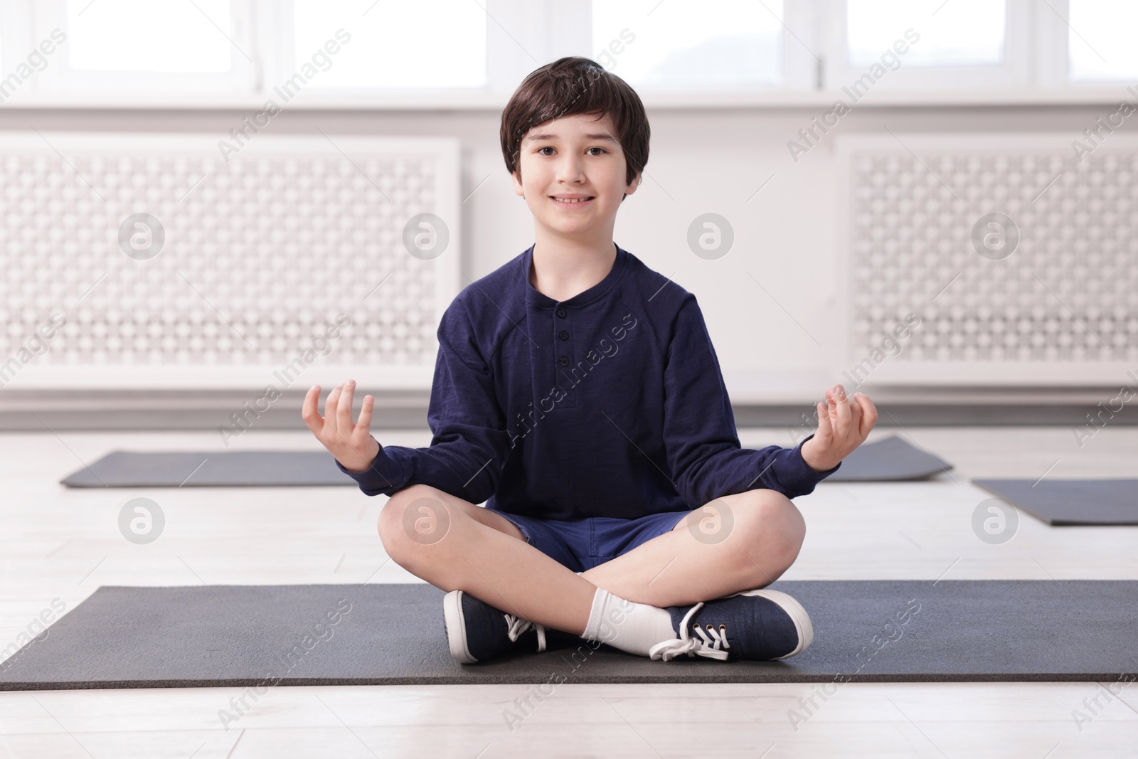 Happy boy practicing yoga on mat indoors Photo of Happy boy practicing yoga on mat indoors