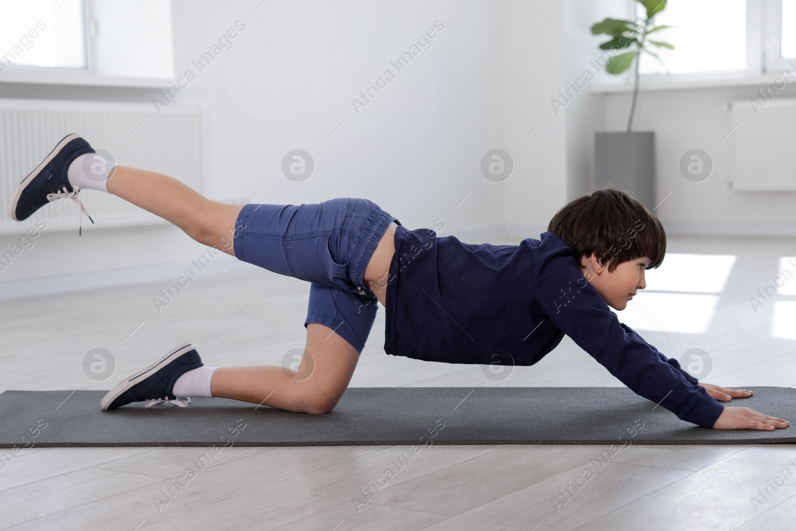 Cute boy practicing yoga on mat indoors Photo of Cute boy practicing yoga on mat indoors