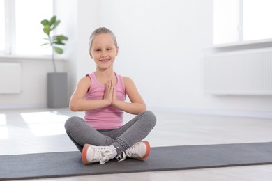 Photo of Happy girl practicing yoga on mat indoors