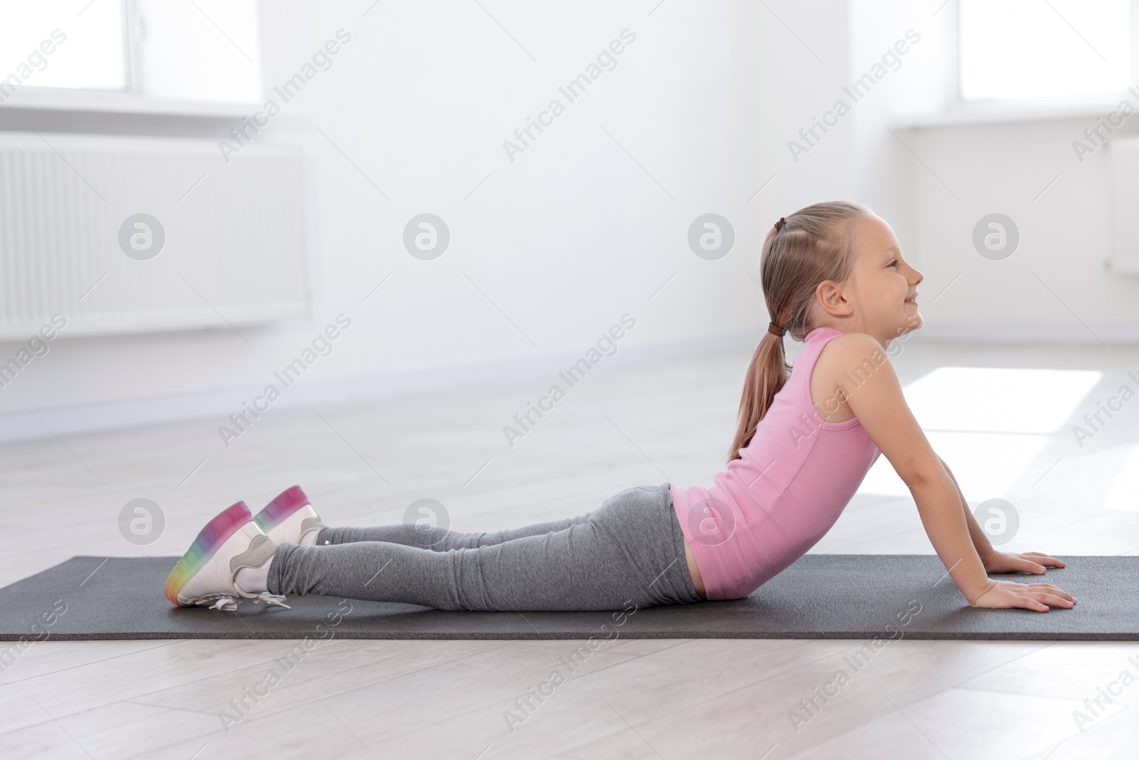 Cute girl practicing yoga on mat indoors Photo of Cute girl practicing yoga on mat indoors