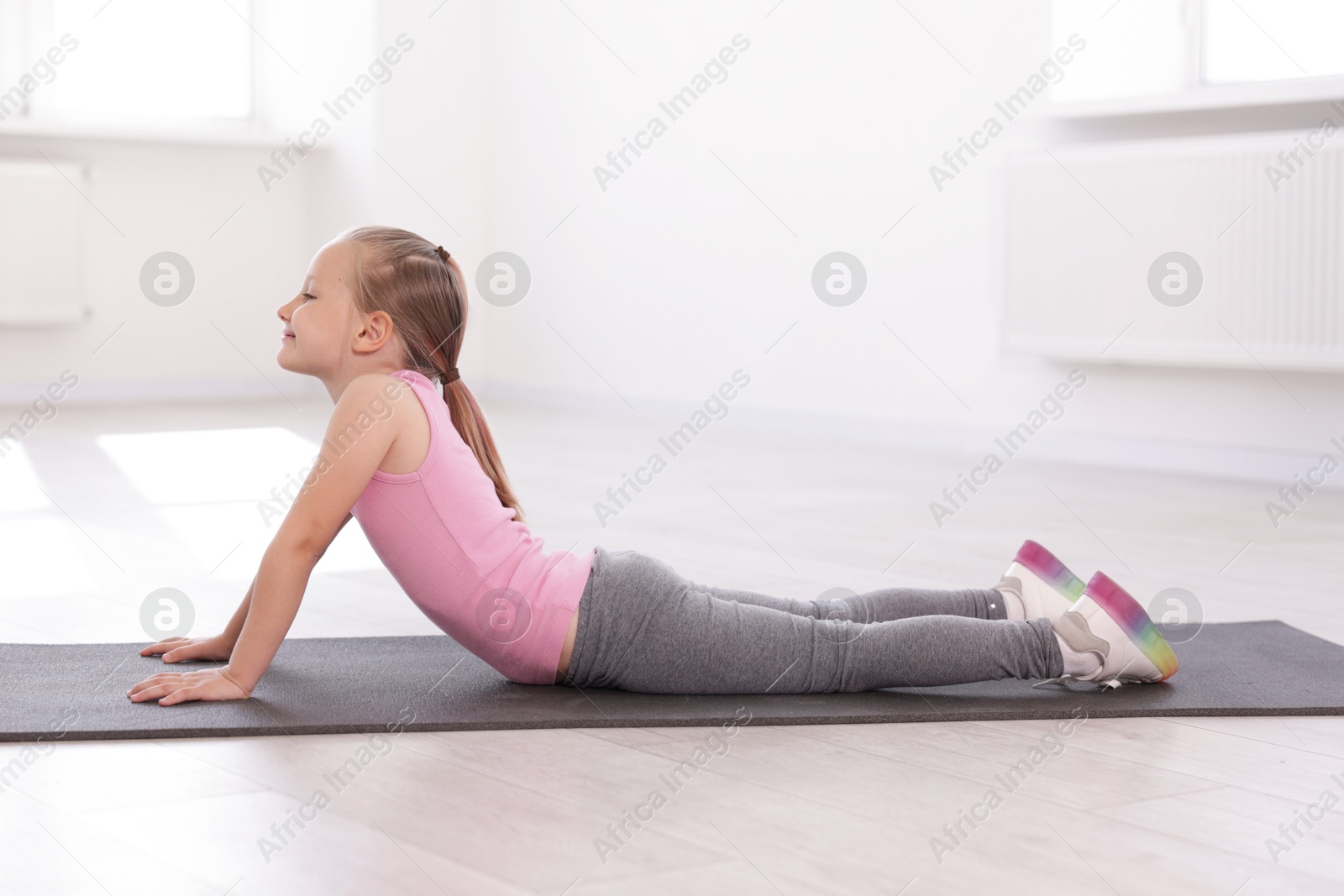 Cute girl practicing yoga on mat indoors Photo of Cute girl practicing yoga on mat indoors