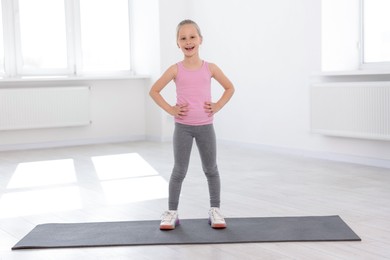 Photo of Happy girl standing on yoga mat indoors