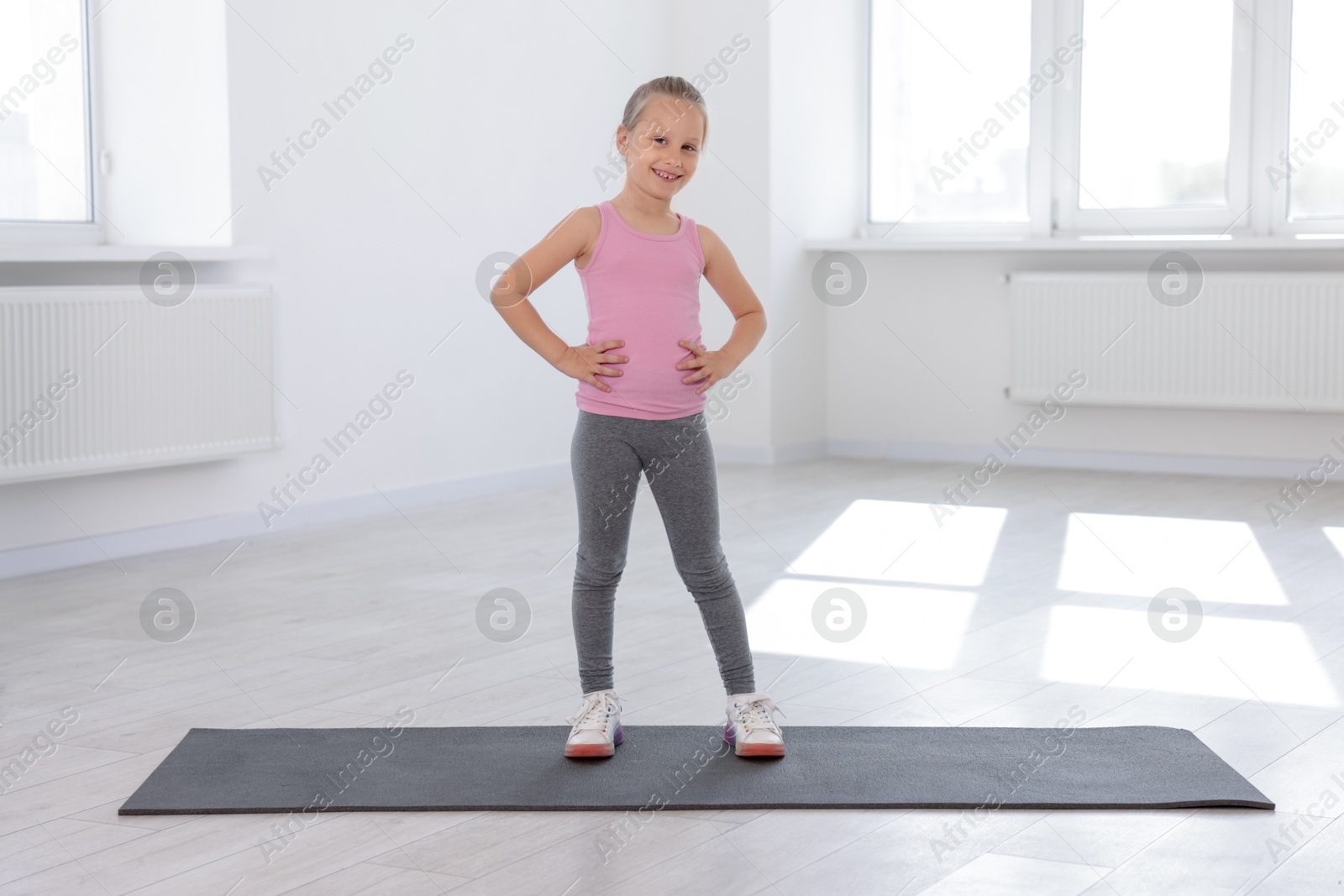 Happy girl standing on yoga mat indoors Photo of Happy girl standing on yoga mat indoors