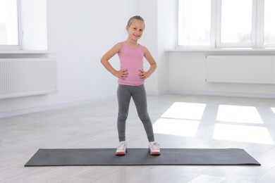 Photo of Happy girl standing on yoga mat indoors