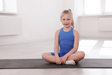 Photo of Happy girl sitting on yoga mat indoors
