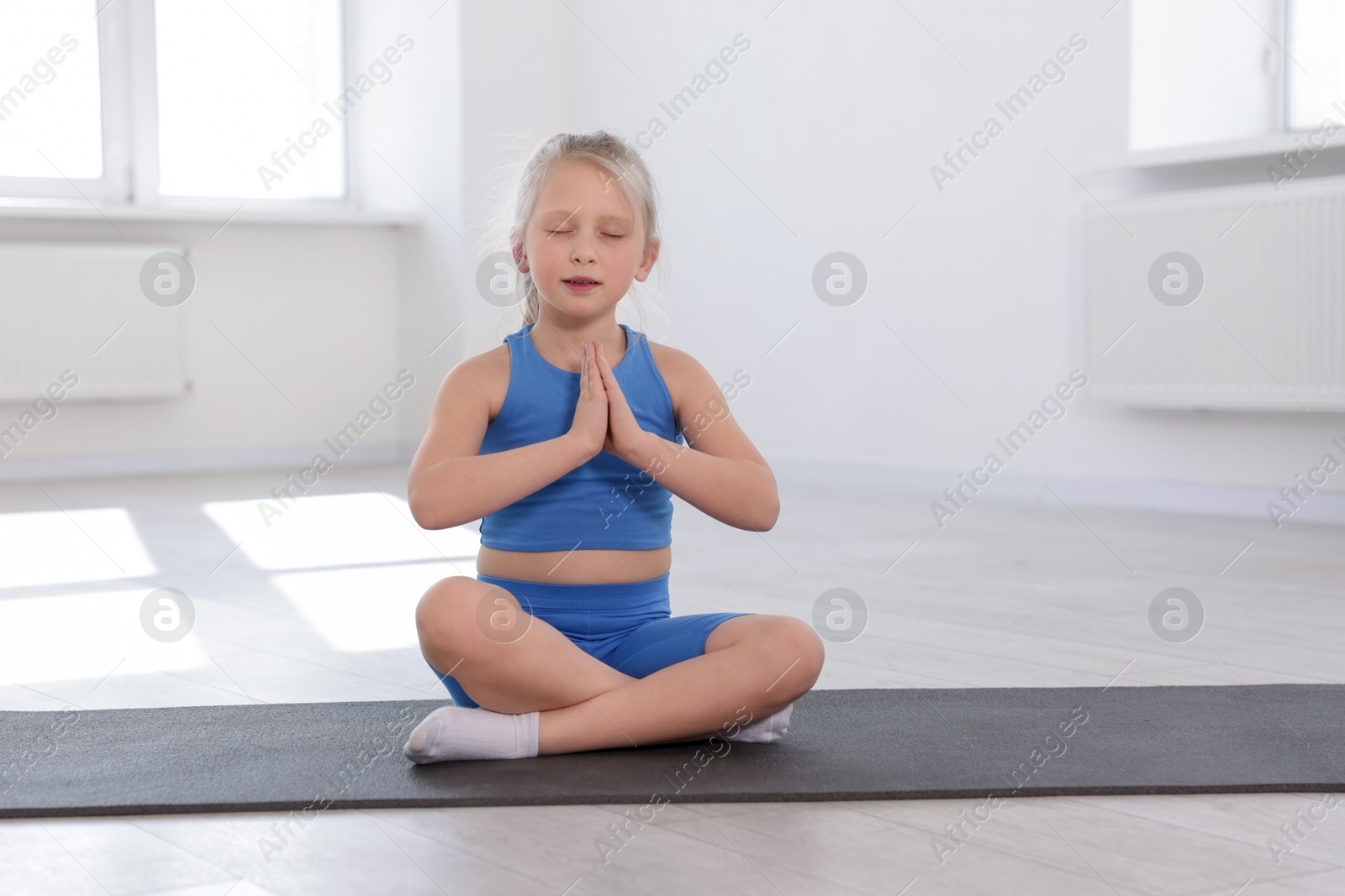 Cute girl meditating on yoga mat indoors Photo of Cute girl meditating on yoga mat indoors