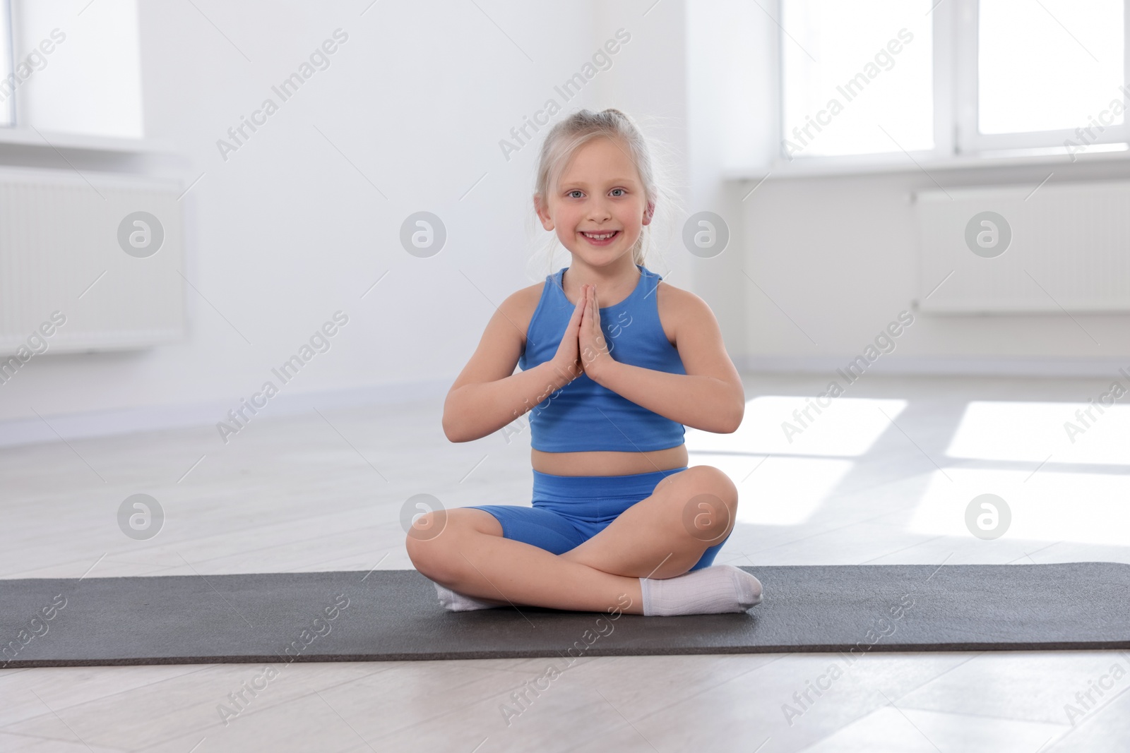 Happy girl practicing yoga on mat indoors Photo of Happy girl practicing yoga on mat indoors