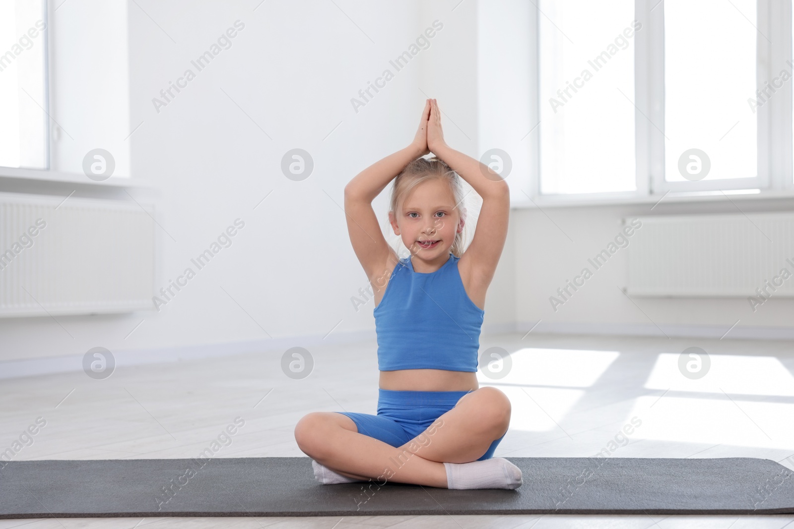 Happy girl practicing yoga on mat indoors Photo of Happy girl practicing yoga on mat indoors