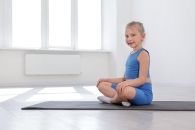 Photo of Happy girl sitting on yoga mat indoors