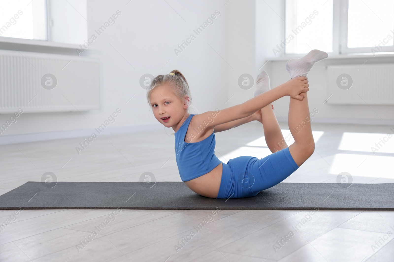 Cute girl practicing yoga on mat indoors Photo of Cute girl practicing yoga on mat indoors