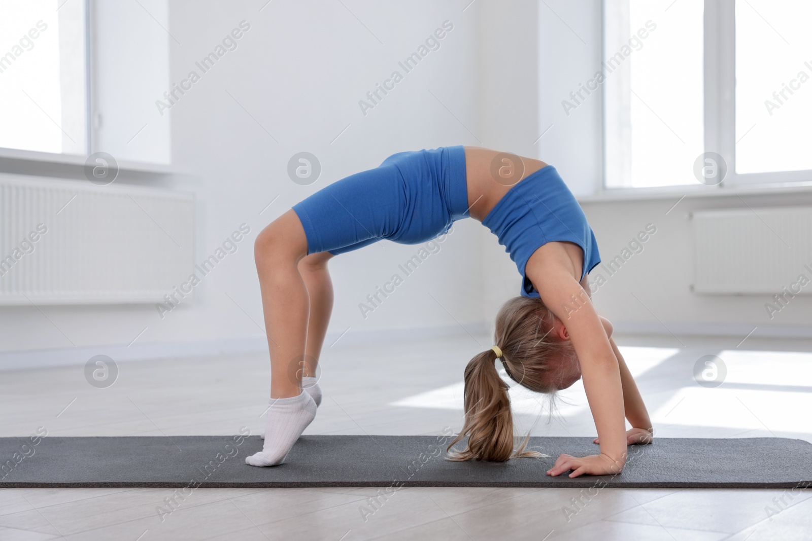 Cute girl practicing yoga on mat indoors Photo of Cute girl practicing yoga on mat indoors