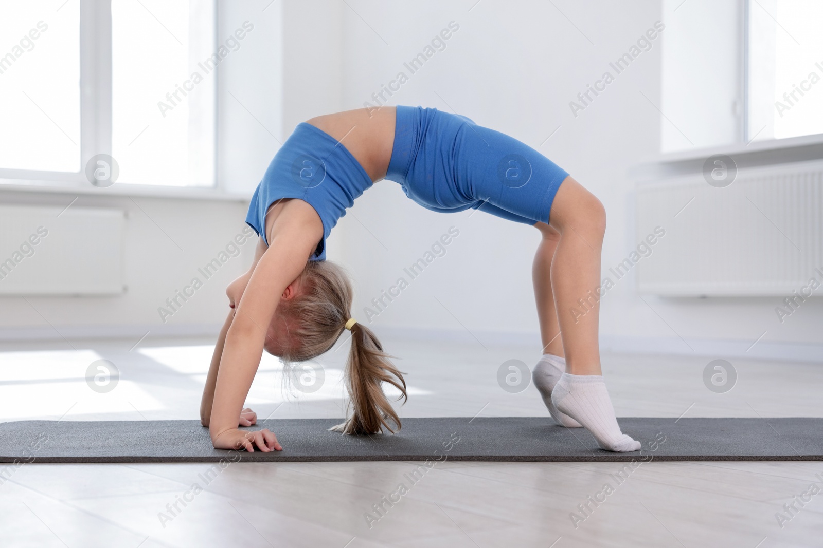 Cute girl practicing yoga on mat indoors Photo of Cute girl practicing yoga on mat indoors