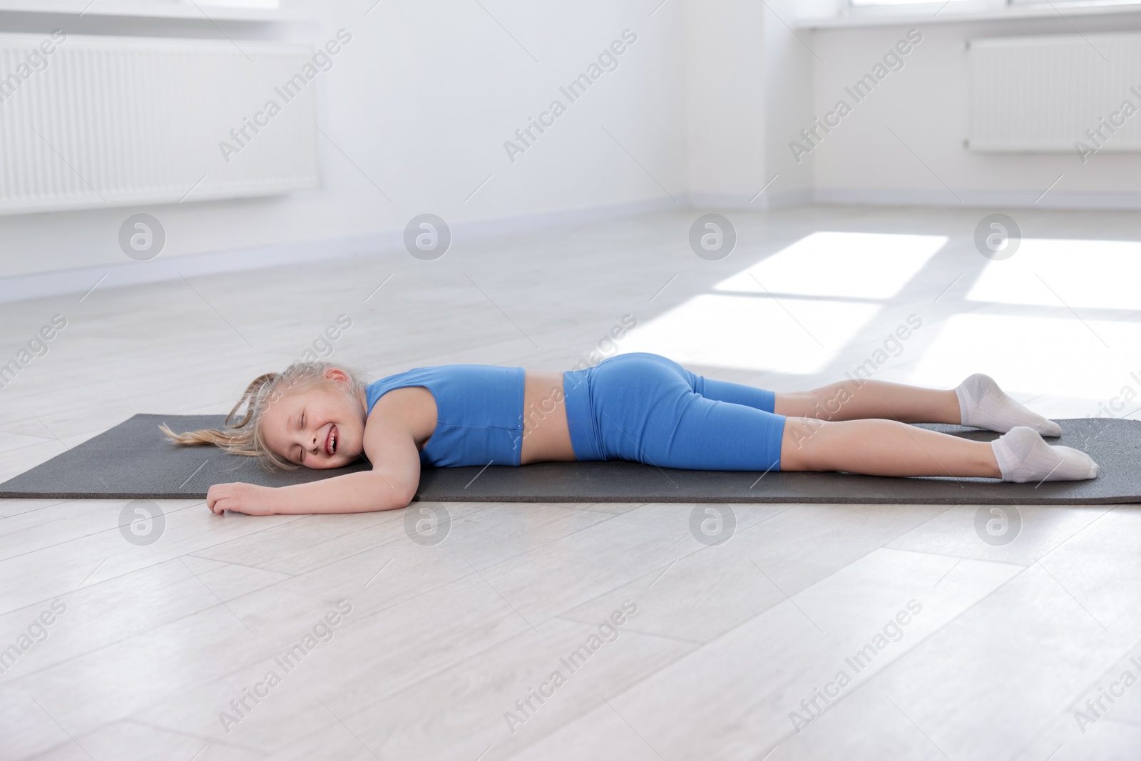 Happy girl lying on yoga mat indoors Photo of Happy girl lying on yoga mat indoors