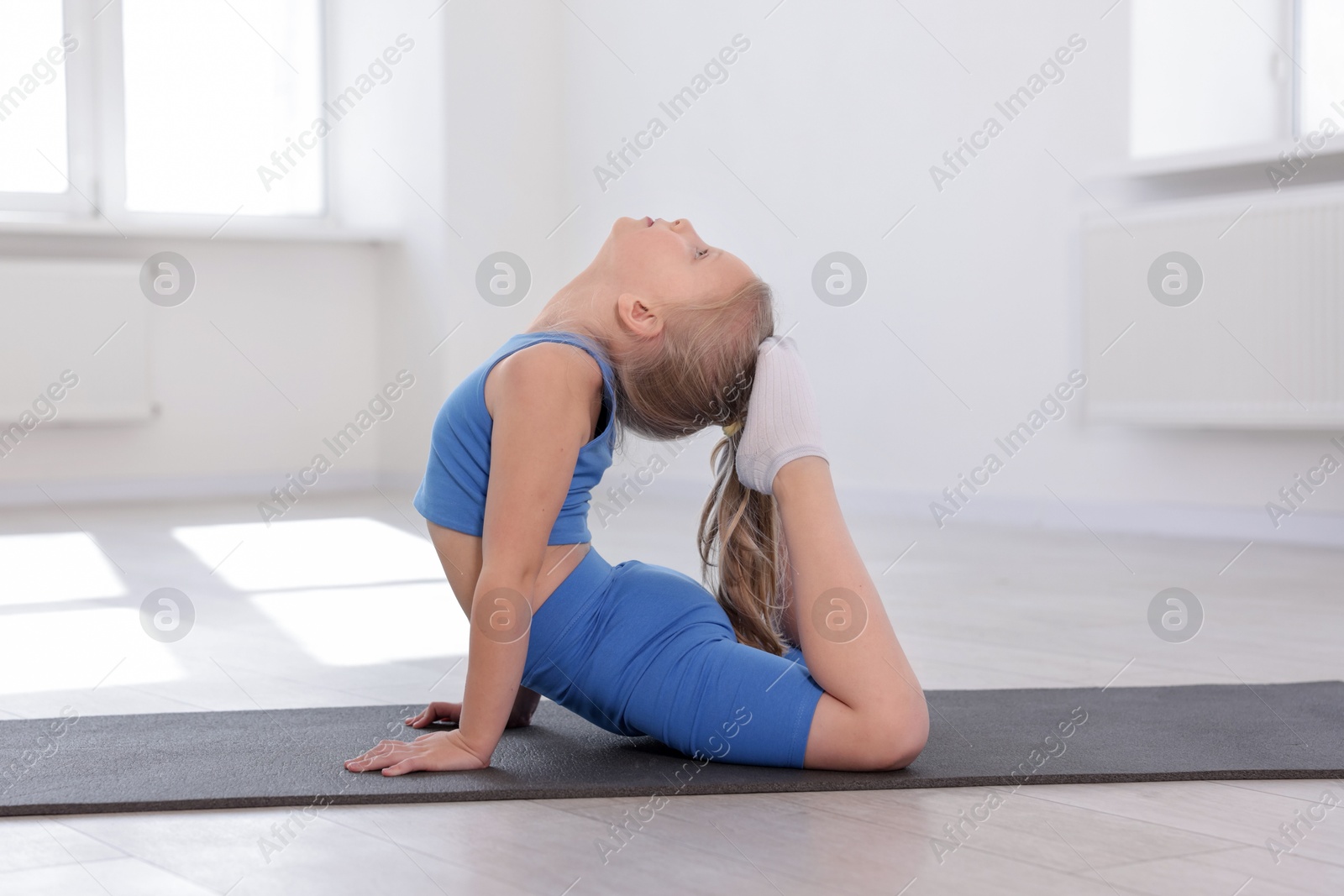 Cute girl practicing yoga on mat indoors Photo of Cute girl practicing yoga on mat indoors