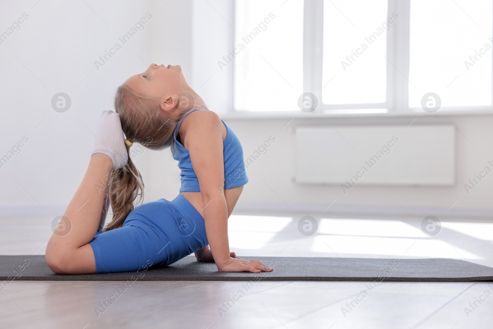 Cute girl practicing yoga on mat indoors Photo of Cute girl practicing yoga on mat indoors