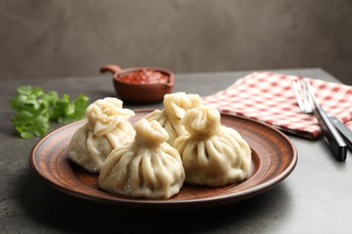 Photo of Delicious khinkali served with sauce on grey table, closeup