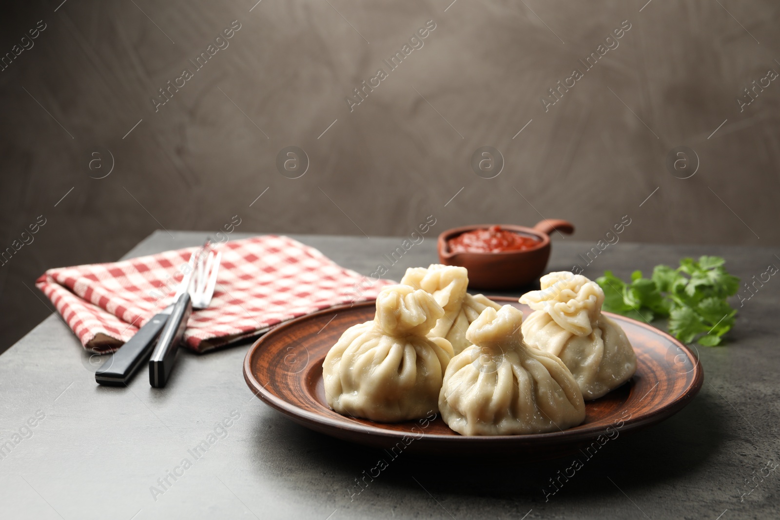 Delicious khinkali served with sauce on grey table Photo of Delicious khinkali served with sauce on grey table