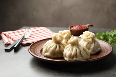 Photo of Delicious khinkali served with sauce on grey table, closeup