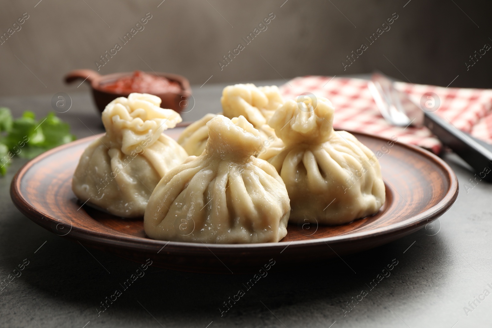 Delicious khinkali served with sauce on grey table, closeup Photo of Delicious khinkali served with sauce on grey table, closeup