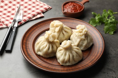 Photo of Delicious khinkali served with sauce on grey table, closeup