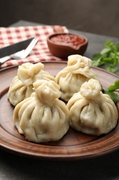 Photo of Delicious khinkali served with sauce on grey table, closeup