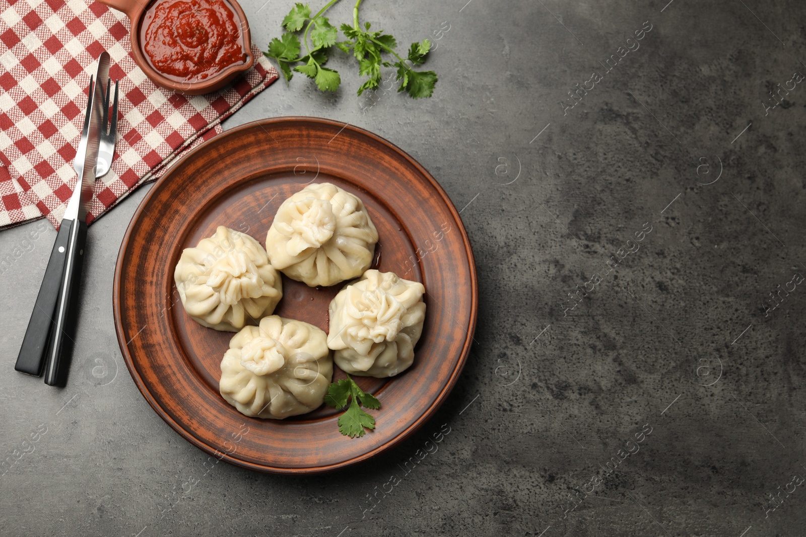 Delicious khinkali served with sauce on grey table, flat lay Photo of Delicious khinkali served with sauce on grey table, flat lay