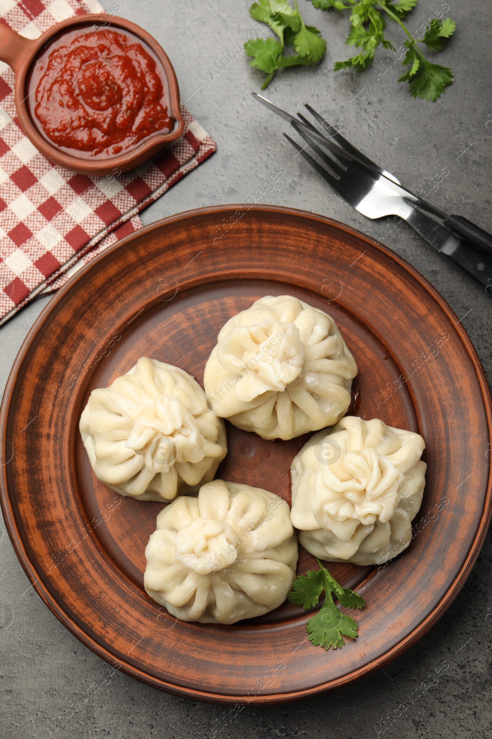 Delicious khinkali served with sauce on grey table, flat lay Photo of Delicious khinkali served with sauce on grey table, flat lay
