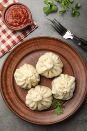 Photo of Delicious khinkali served with sauce on grey table, flat lay
