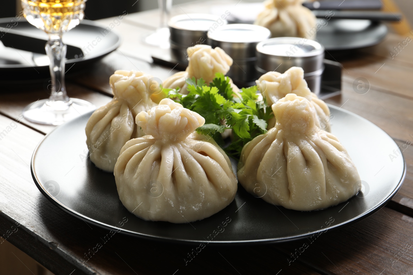 Delicious khinkali served with cilantro on wooden table, closeup Photo of Delicious khinkali served with cilantro on wooden table, closeup