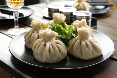 Photo of Delicious khinkali served with cilantro on wooden table, closeup