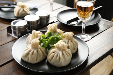 Photo of Delicious khinkali served with cilantro on wooden table, closeup