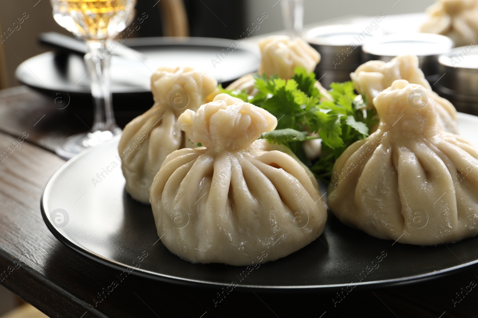 Delicious khinkali served with cilantro on wooden table, closeup Photo of Delicious khinkali served with cilantro on wooden table, closeup