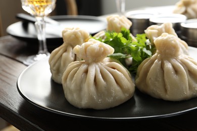 Photo of Delicious khinkali served with cilantro on wooden table, closeup