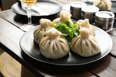 Photo of Delicious khinkali served with cilantro on wooden table, closeup