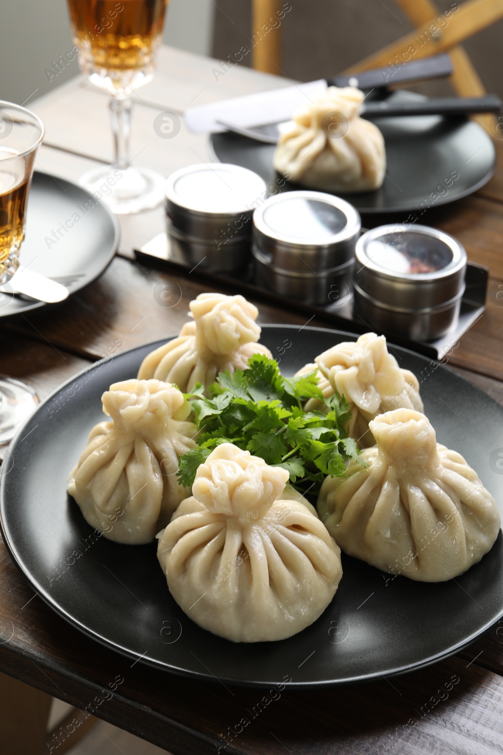 Delicious khinkali served with cilantro on wooden table, closeup Photo of Delicious khinkali served with cilantro on wooden table, closeup