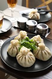Photo of Delicious khinkali served with cilantro on wooden table, closeup