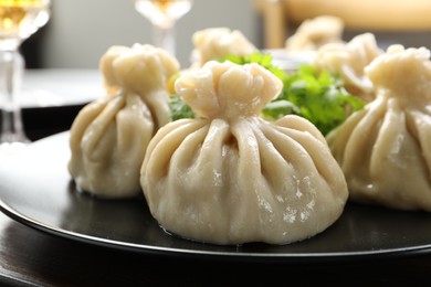 Photo of Delicious khinkali served with cilantro on wooden table, closeup