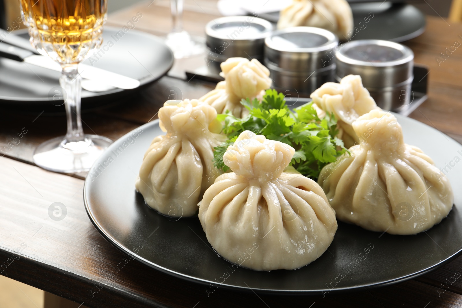 Delicious khinkali served with cilantro and wine on wooden table, closeup Photo of Delicious khinkali served with cilantro and wine on wooden table, closeup