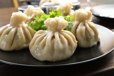 Photo of Delicious khinkali served with cilantro on wooden table, closeup