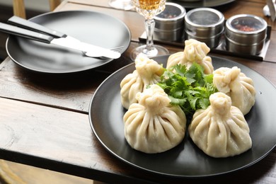Photo of Delicious khinkali served with cilantro on wooden table, closeup