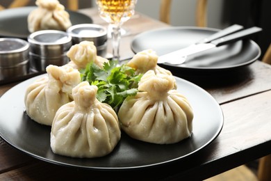 Photo of Delicious khinkali served with cilantro on wooden table, closeup