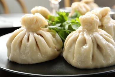 Photo of Delicious khinkali served with cilantro on table, closeup